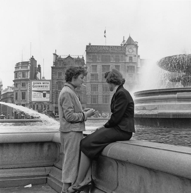 A pair of young women by the fountains in Trafalgar Square, London, 1953.