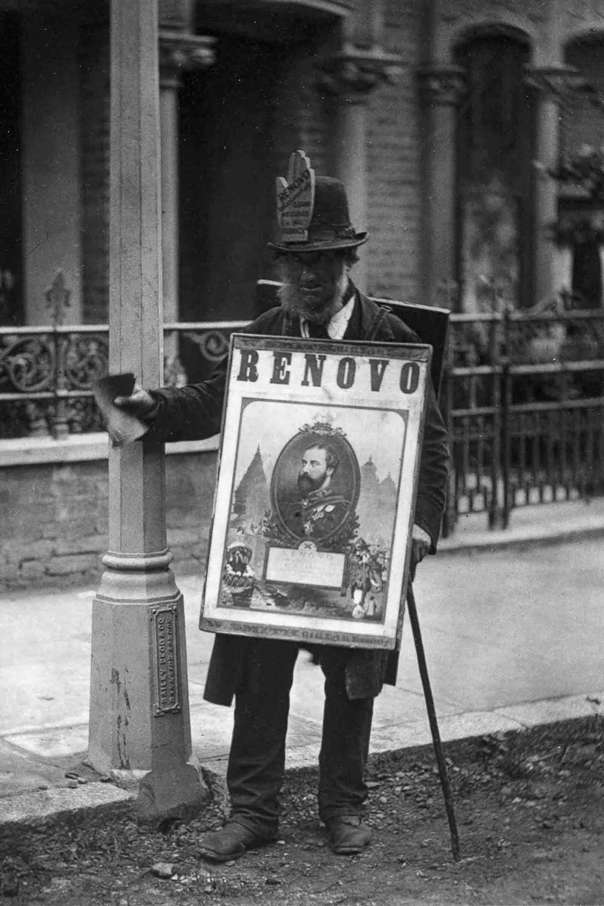 A man wears a sandwich-board advertisement, 1877.