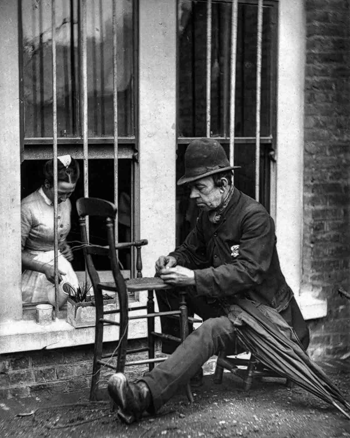 Caney” the clown weaves cane strips into the seat of a wooden chair, 1877.