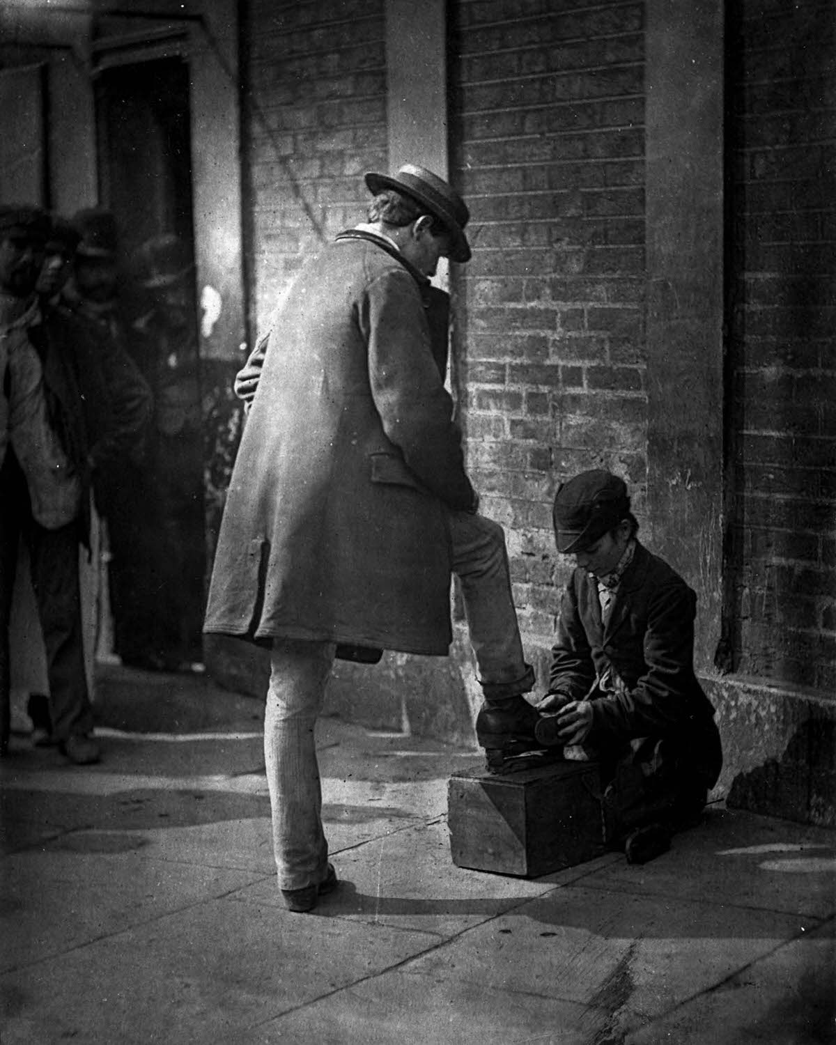 A shoeshine boy at work, 1877.