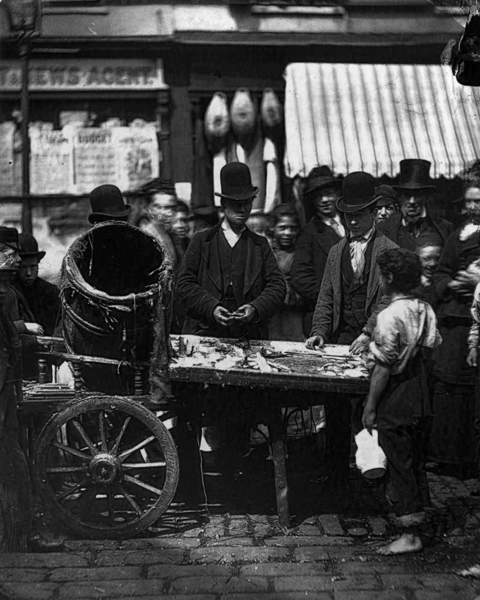 Costermonger Joseph Carney sells fresh herring from his barrow in the street market between Seven Dials and Five Dials in London, 1877