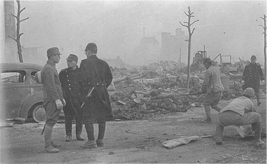 Soldiers and police officers band together in order to collect the charred remains of men, women, and children. March 10, 1945. Tokyo, Japan.