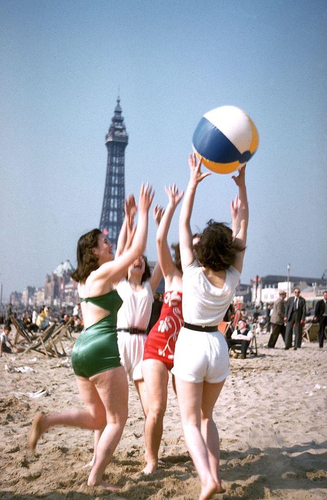 A group of young women play with a beach ball on Blackpool beach, 1955.