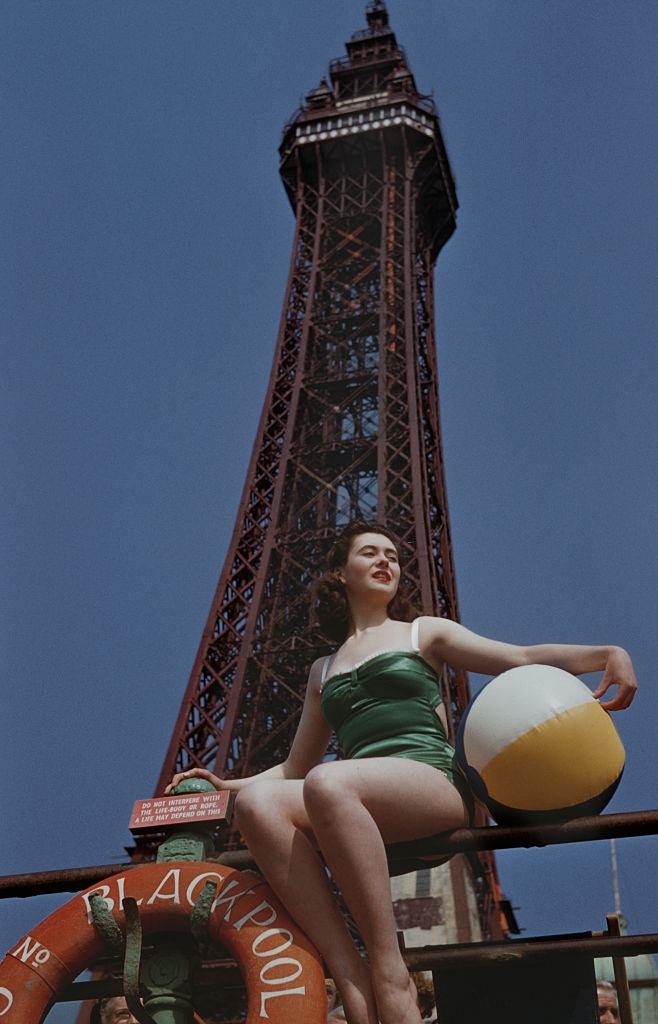 A young woman with a beach ball in front of Blackpool Tower in Blackpool, Lancashire, UK, 23rd June 1955.