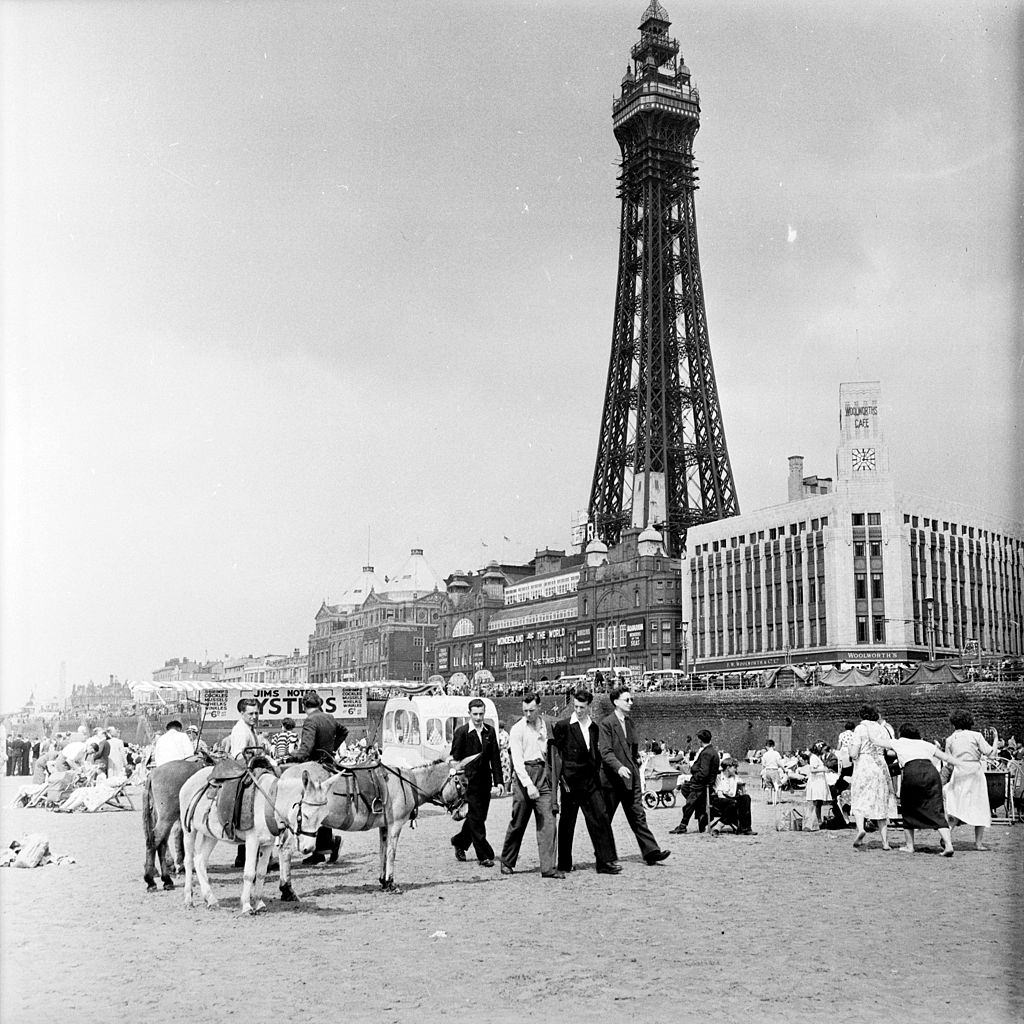 Tourists on the beach at Blackpool with the Blackpool Tower behind them, 1953.