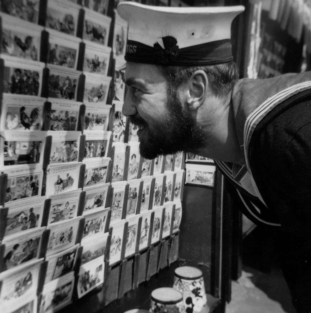 A sailor looking at a selection of postcards at the seaside in Blackpool, 1951.