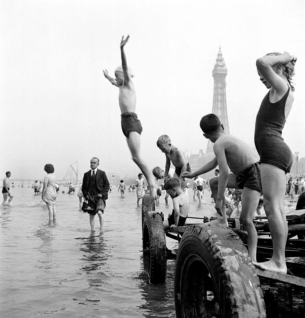 Children in swimming costumes jump into the sea, Blackpool, 1955.
