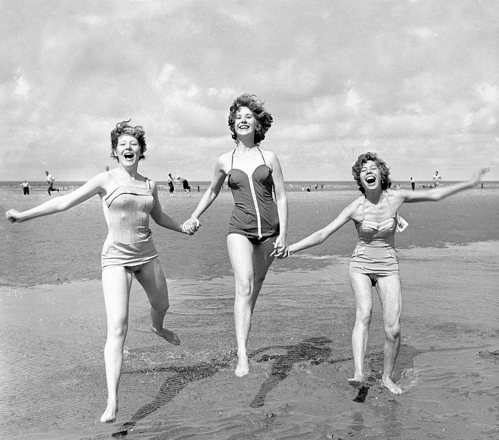 Three girls holding hands on the beach at blackpool August 1958