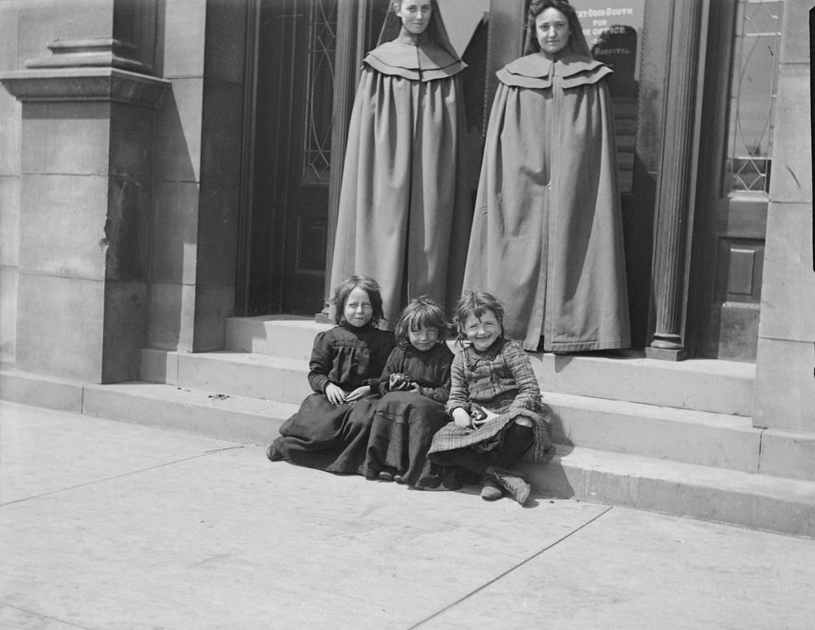 Two women and three girls seated in front of St. Luke’s Hospital