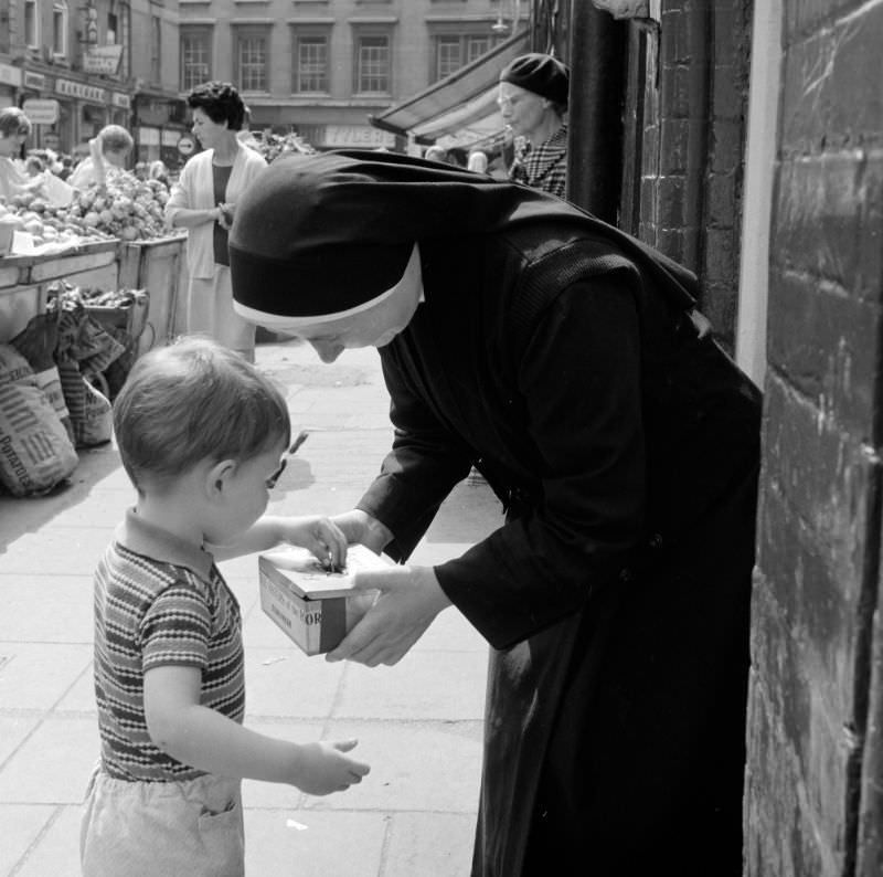 Little boy putting money in nun's collection tray, Dublin, 1969