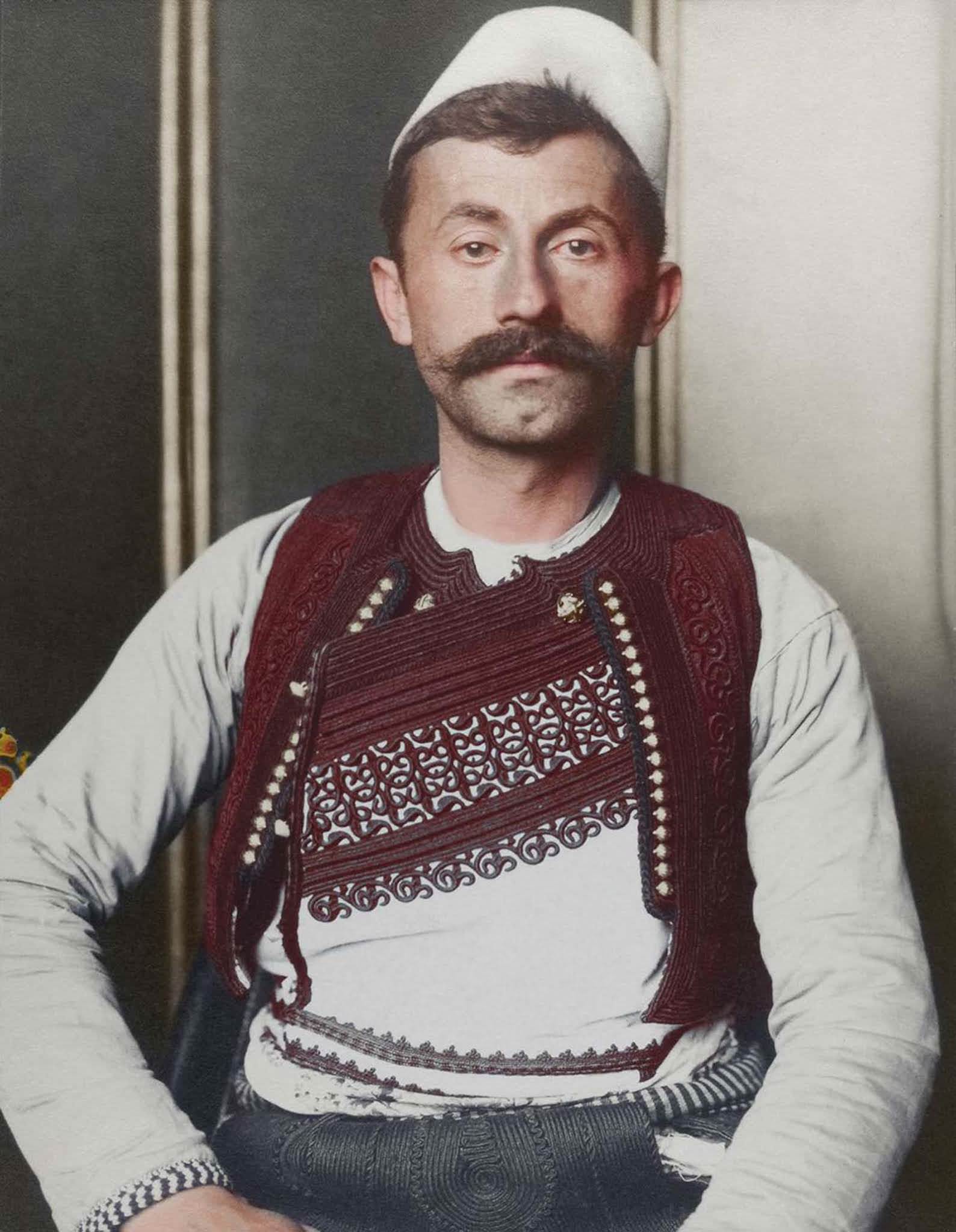 Albanian soldier.” The truncated brimless felt cap is known as a qeleshe, whose shape was largely determined by region and molded to one’s head. The vest, known as a jelek or xhamadan, was decorated with embroidered braids of silk or cotton. Its color and decoration denoted the region where the wear