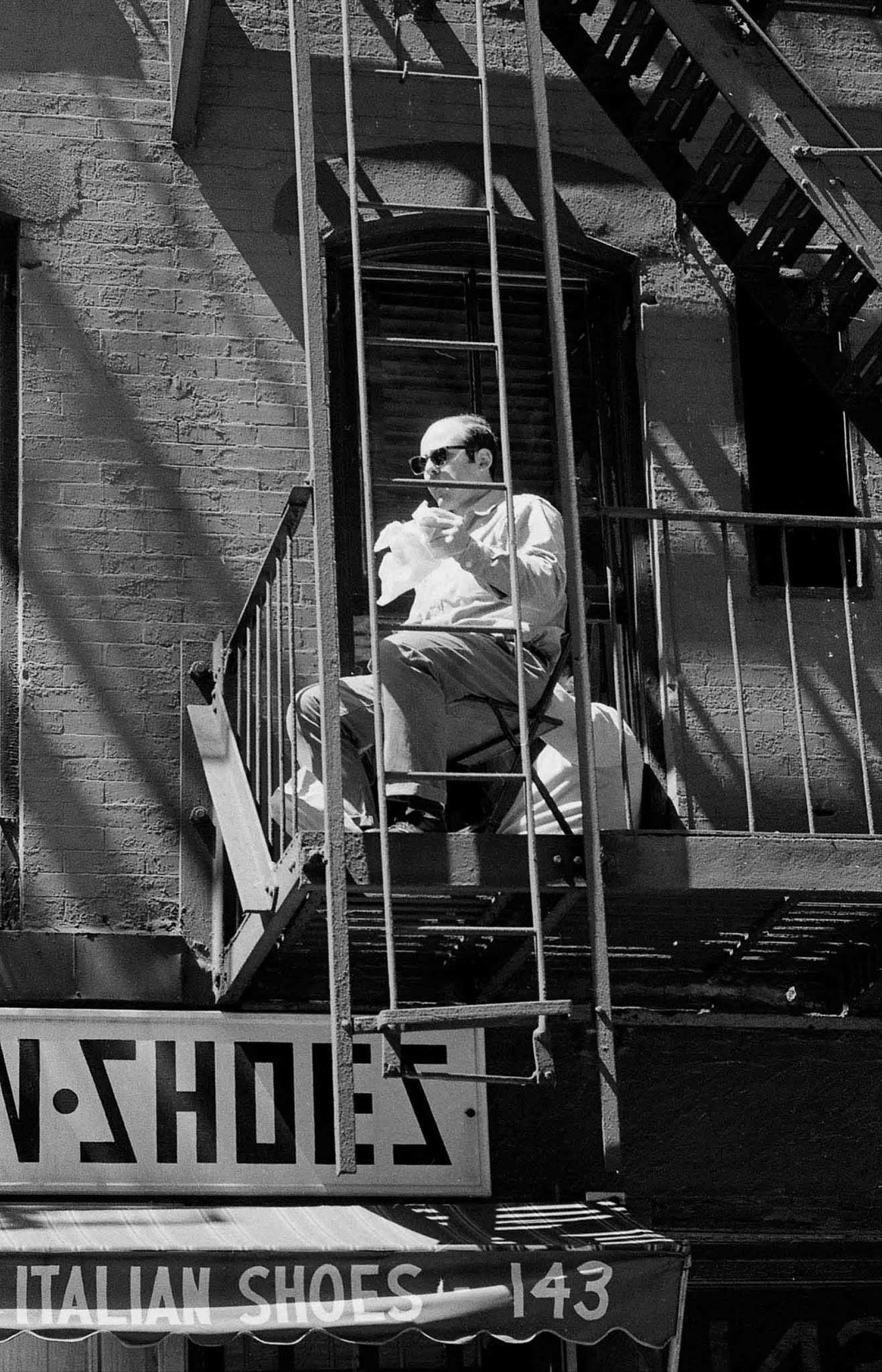 A Little Italy resident watches the production while eating lunch on his fire escape.