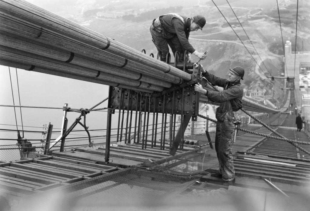 Workers on the catwalks bundling the cables during the construction of the cables of the Golden Gate Bridge, 1935.