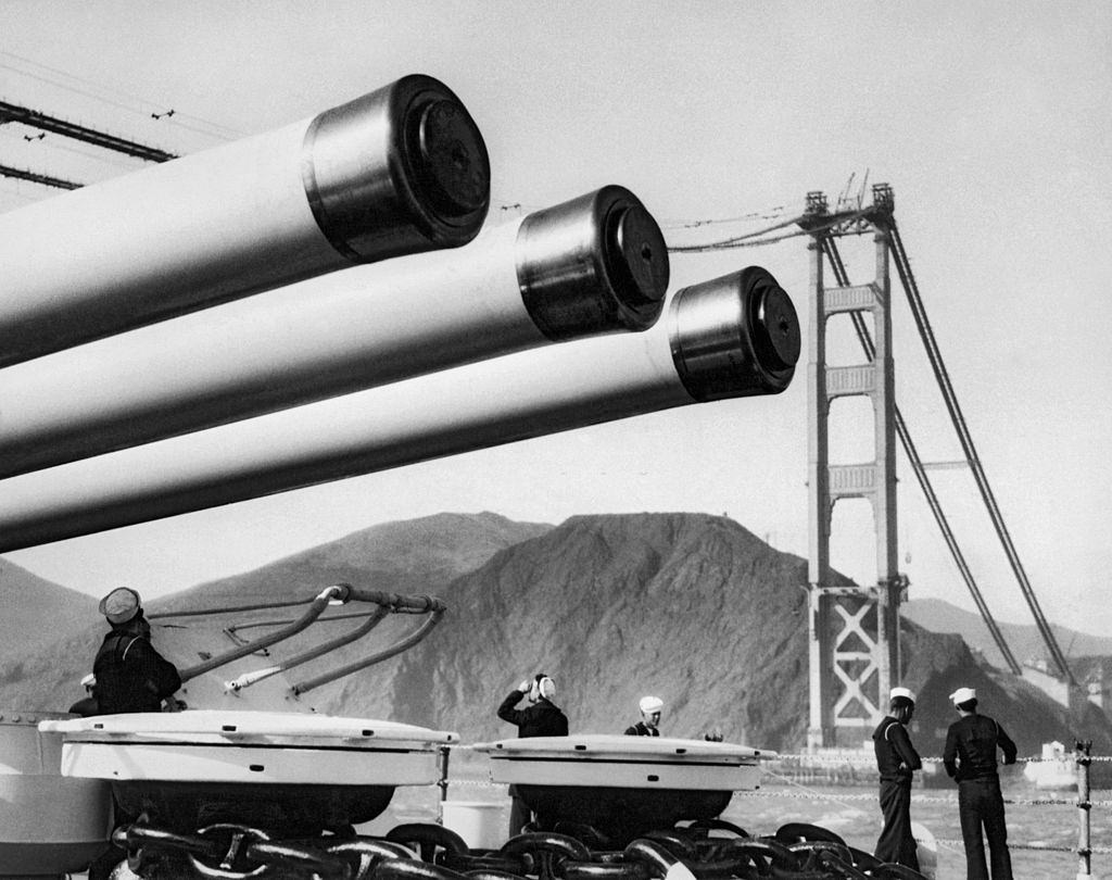 A US Navy battleship cruises under the cables of the Golden Gate Bridge as it is being built, 1936.