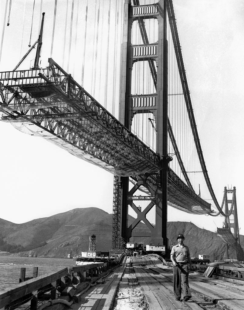 A workman walks on the levee that connects Fort Point to the south tower of the Golden Gate Bridge while it is under construction, 1936.
