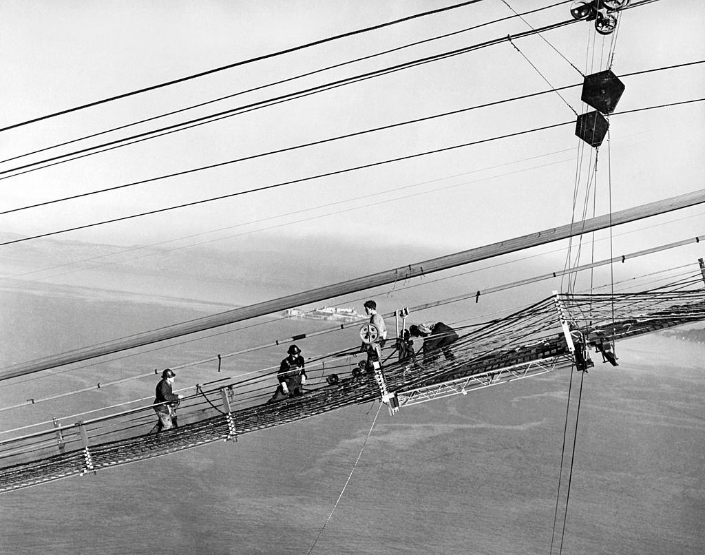 Construction of the Golden Gate Bridge with men on the catwalks working on the cables, San Francisco, 1937.