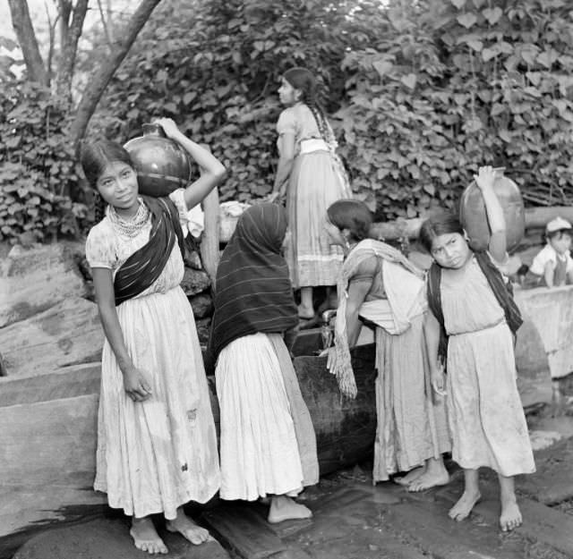 Young girls get water in large jugs in Mexico City.