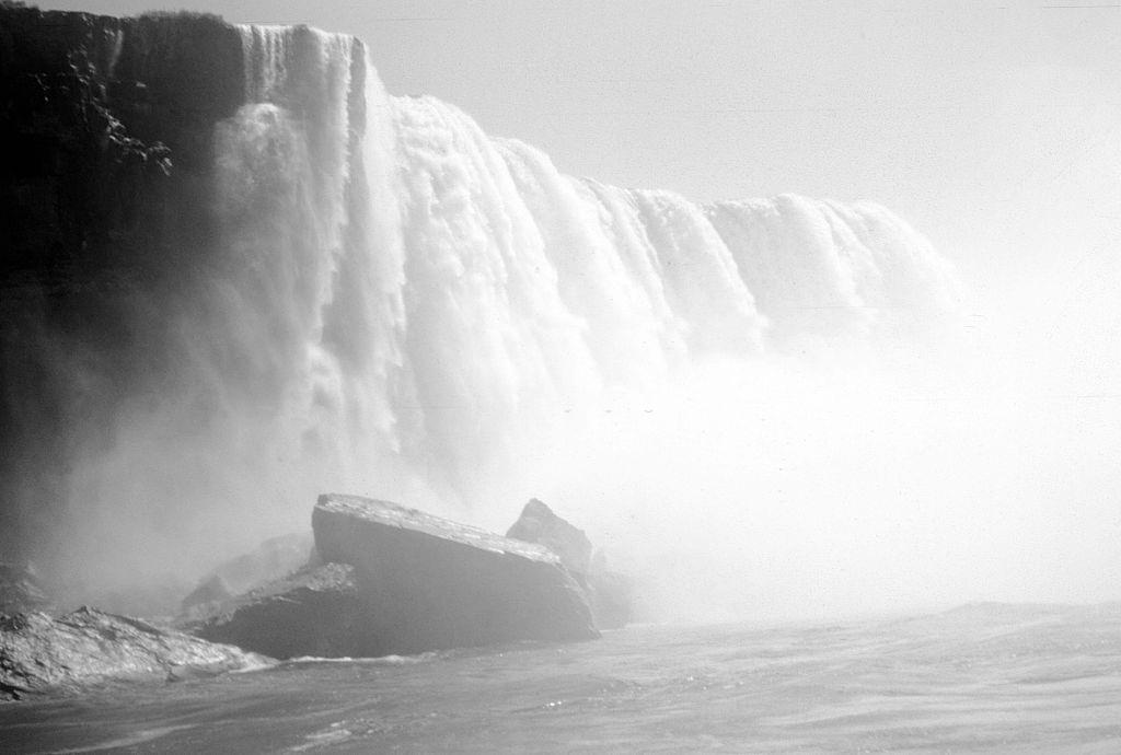 Niagara falls, viewed from a tourist boat, the water of the falls throwing up mist, 1953.