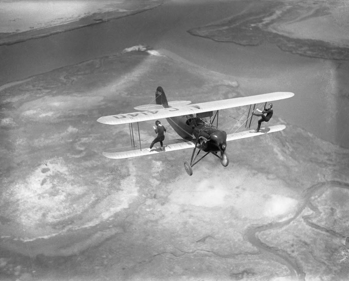 Billy Bomar and Uva Kimmey of the Howard Flying Circus wing-walk on a biplane over New York State, 1930.