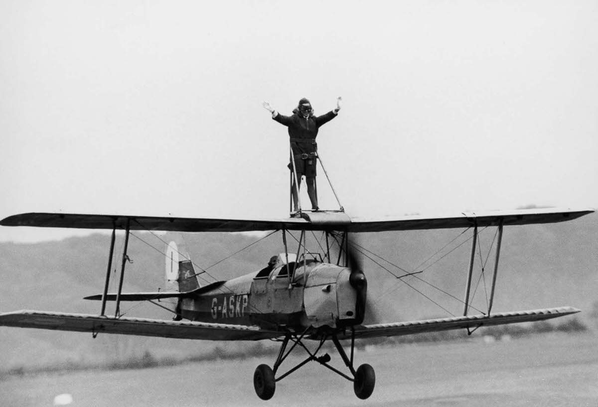 Jacqui Cheesman rides the wing of a Tiger Moth biplane at Wycombe Air Park, Buckinghamshire, England, 1968.