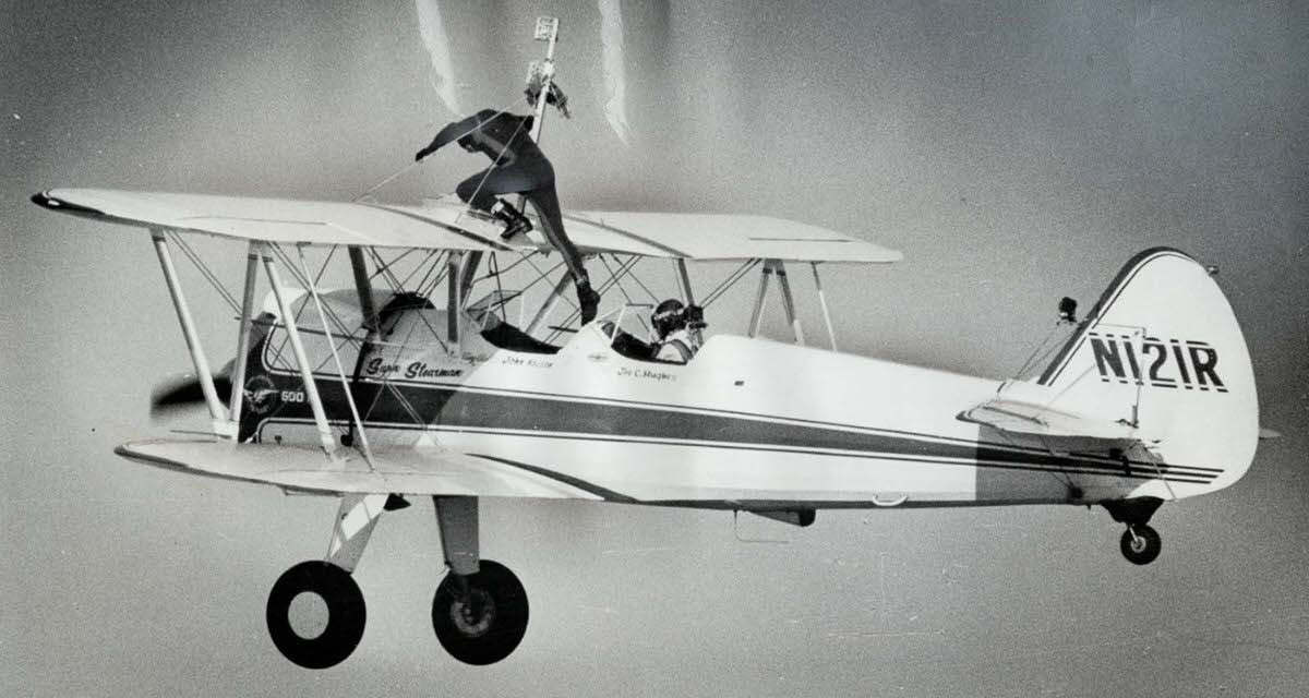 John Kazian mounts the wing of a Stearman Trainer plane flying over Niagara Falls, 1971.