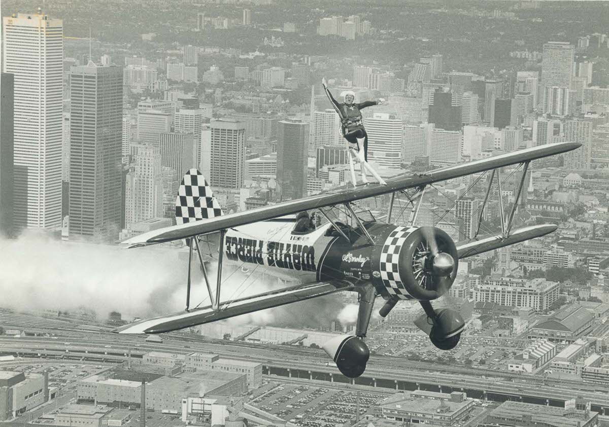 Carol Lynne rides atop a biplane piloted by her husband over Toronto, 1982.