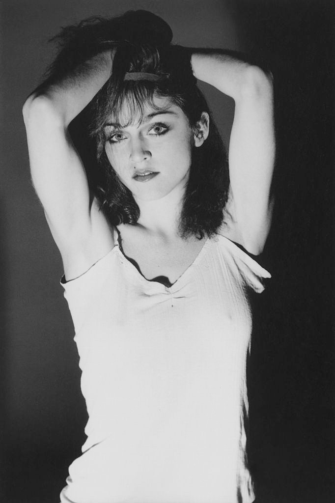 Madonna in a cotton camisole, holding her dark, shoulder-length crimped hair, 1978.