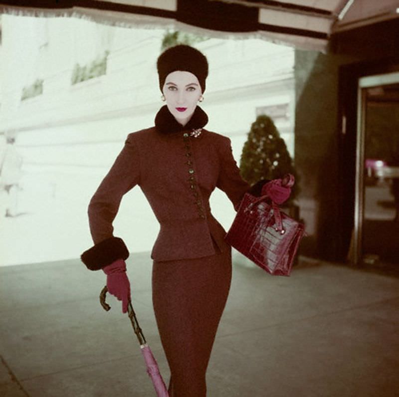Dovima wearing a brown flannel suit with a red velvet collar, matching felt hat with grosgrain band of red and blue silk twill scarf, 1951