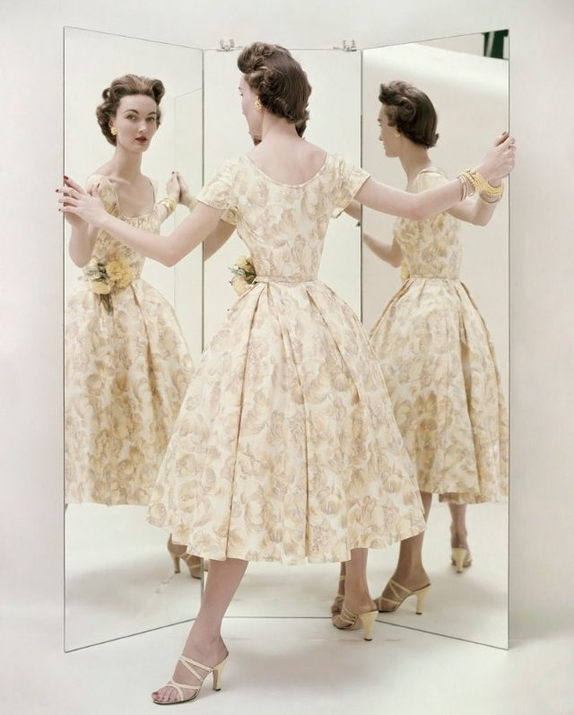 Evelyn Tripp wearing a pale yellow summer party dress by Kane, with matching mules by Valley, 1954