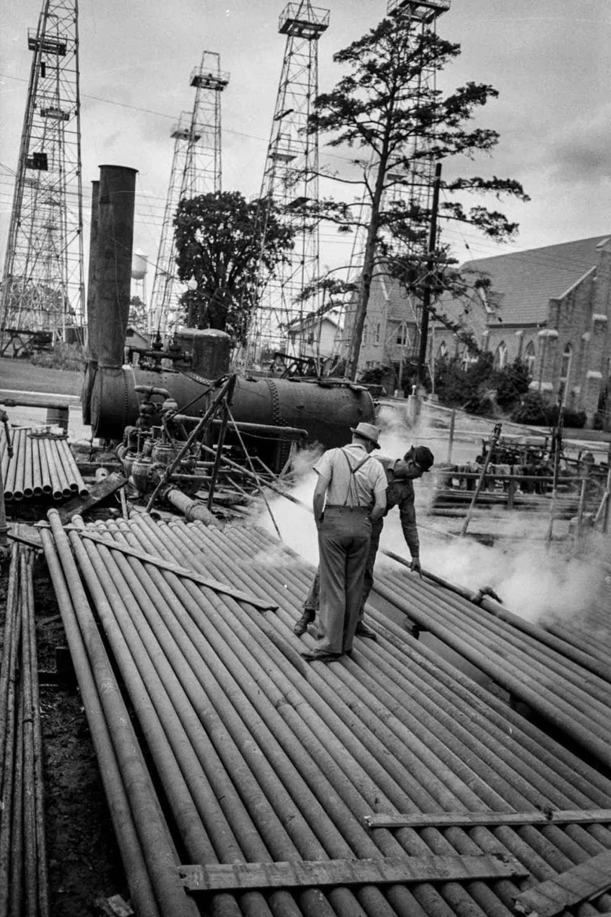 Workers inspect sections of drill pipe.