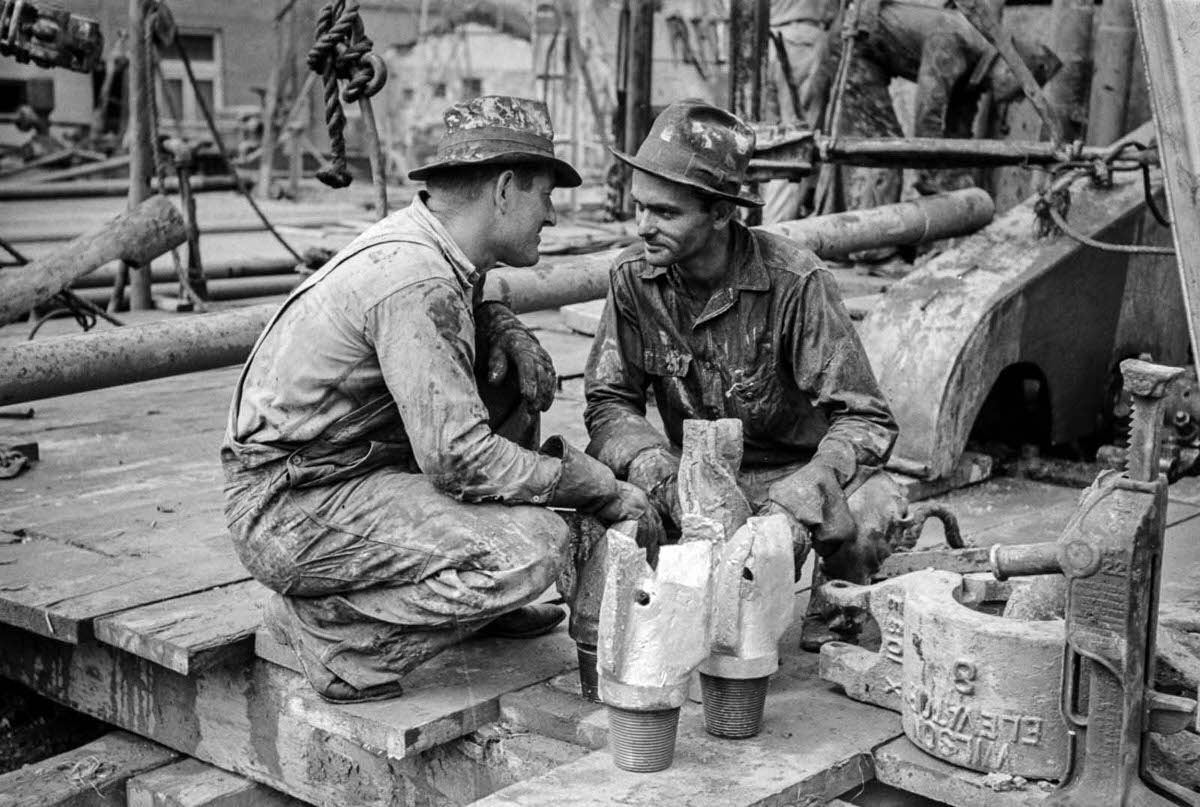 Workers confer over drill bits.