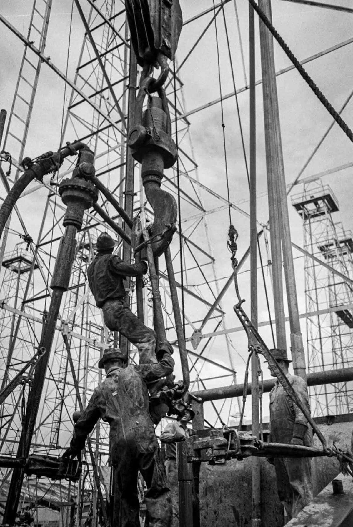 A worker rides the traveling block up to the top of the derrick.