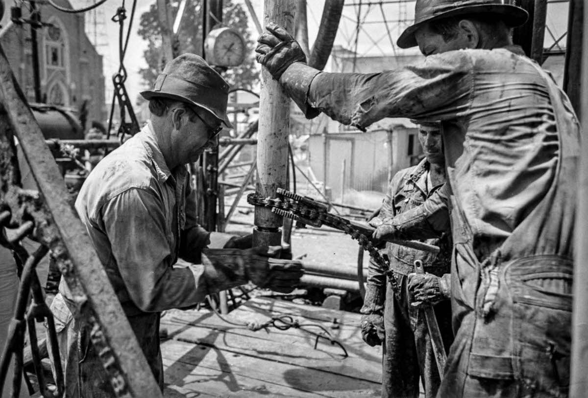 A worker screws a nipple onto the end of a drill stem for a test to determine direction and draft of drilling operations.