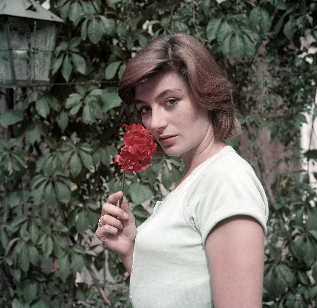 Anouk Aimée poses takes a flower in her hand, 1955.