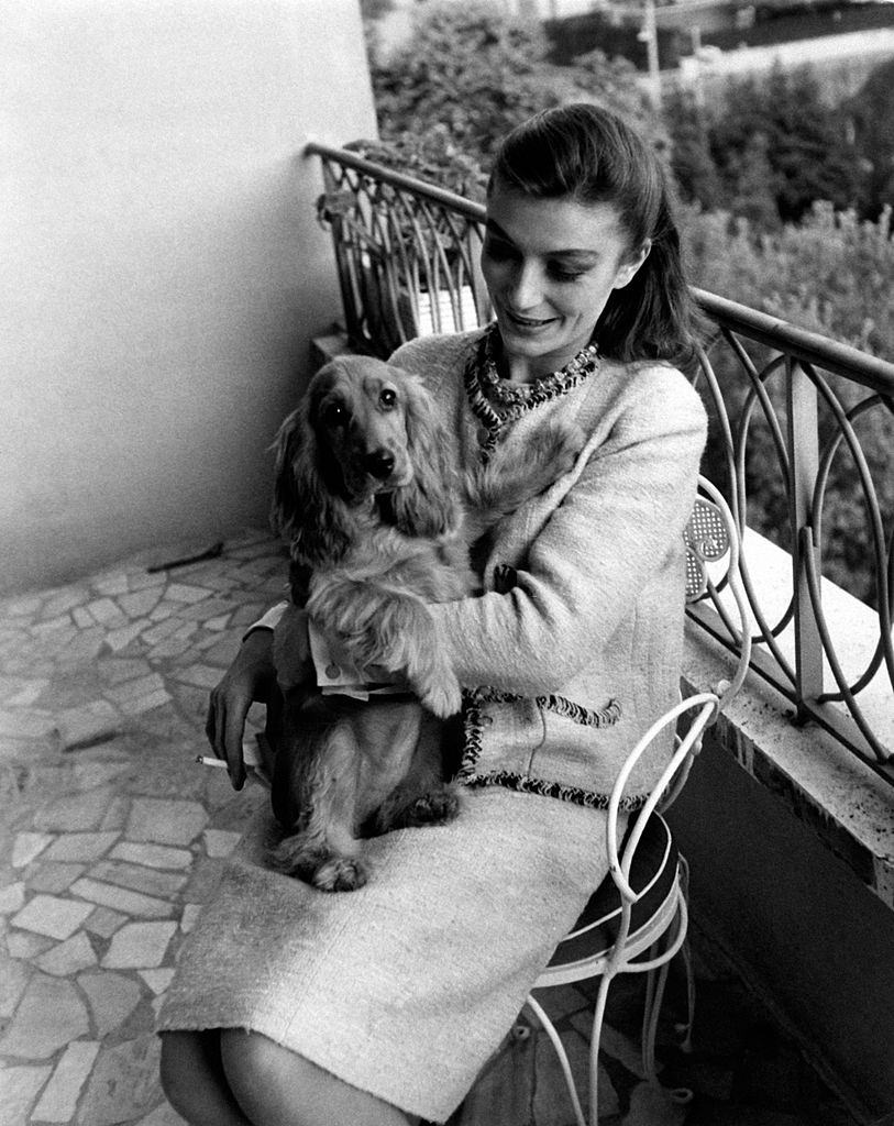 Anouk Aimée sitting in the balcony with her female dog Lulù in her arms in her home in Rome, 1963.