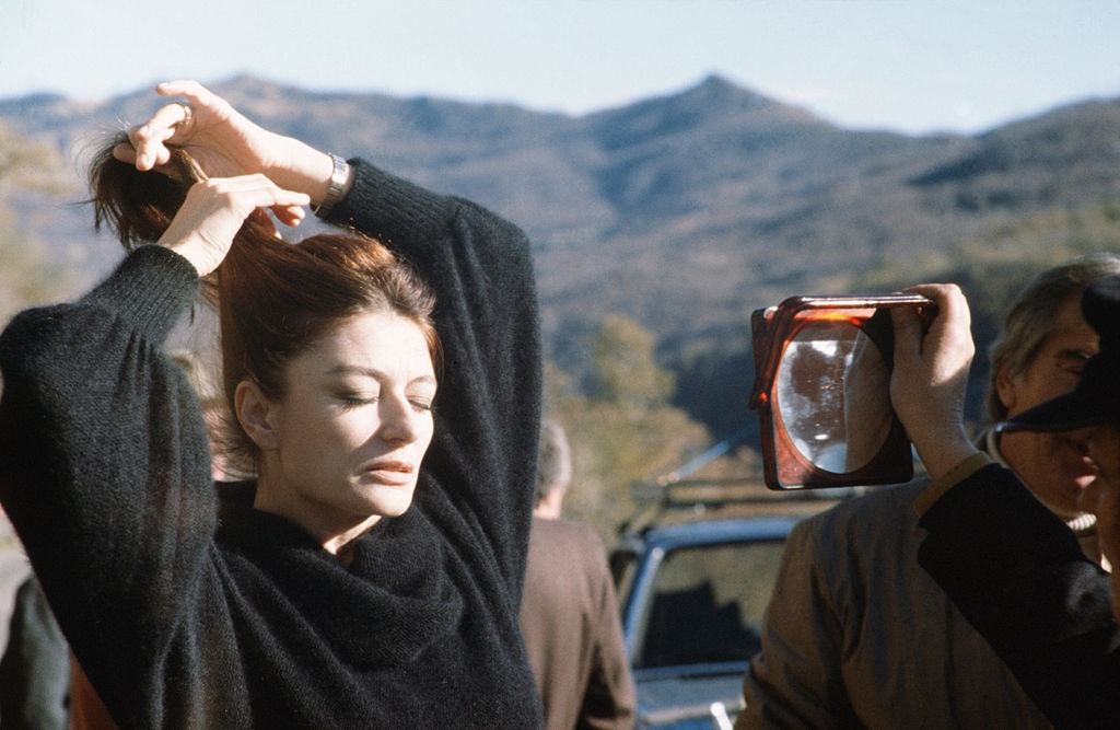 Anouk Aimée fixing her hair in front of a mirror, 1975.