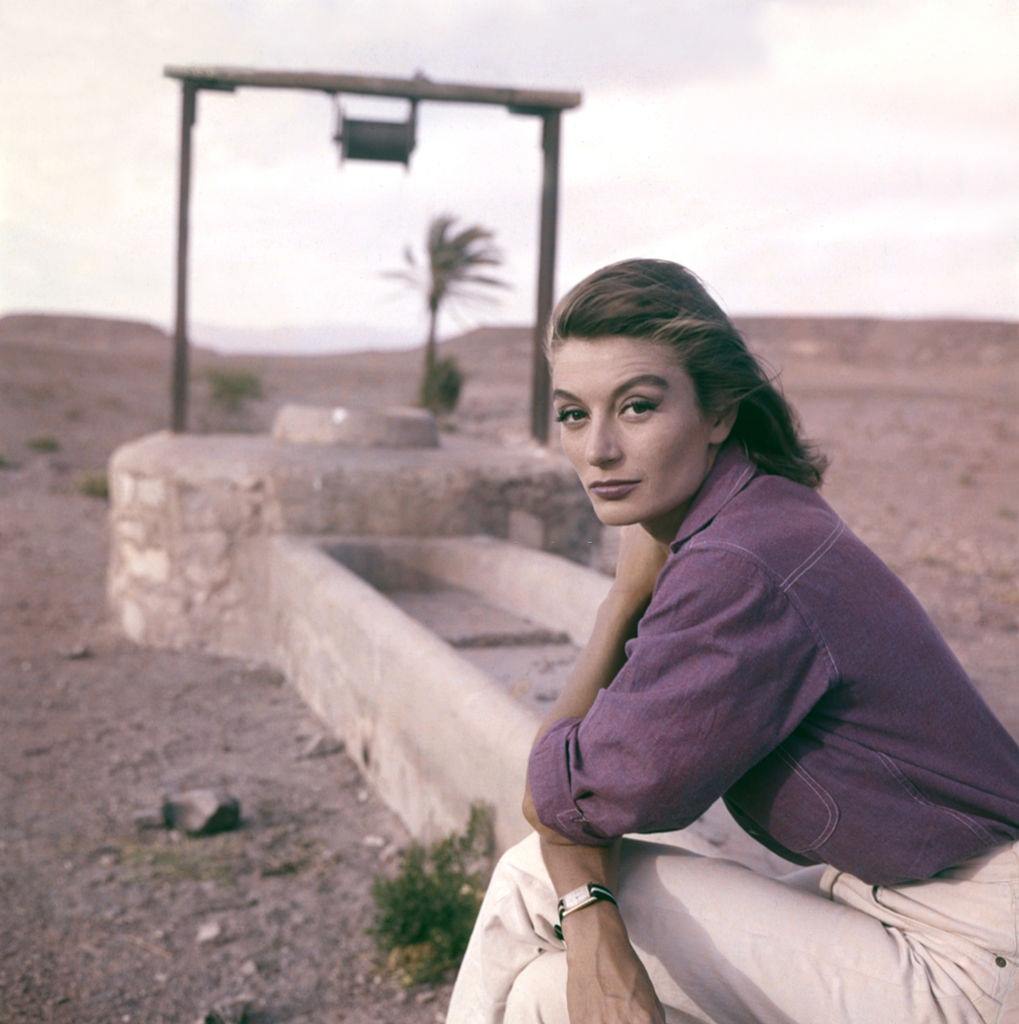 Anouk Aimée sitting on a water-hole in the desert, 1960s.