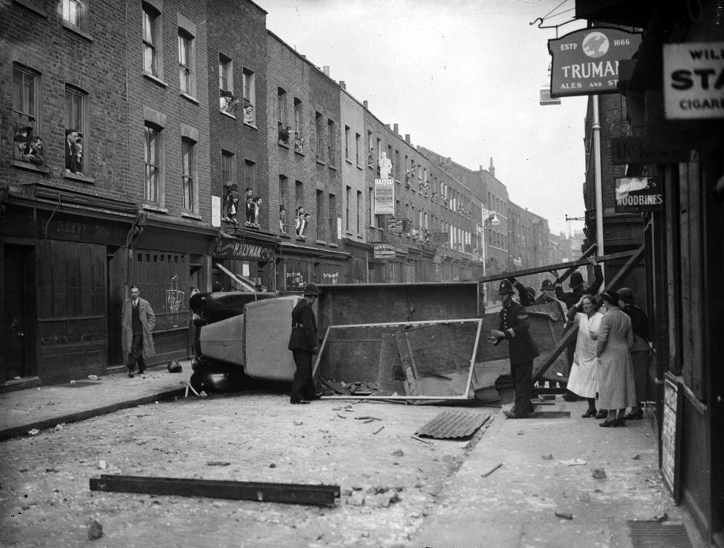 Police remove an overturned lorry used as a barricade during the Communist-Fascist riots in Cable Street, 4th October 1936.