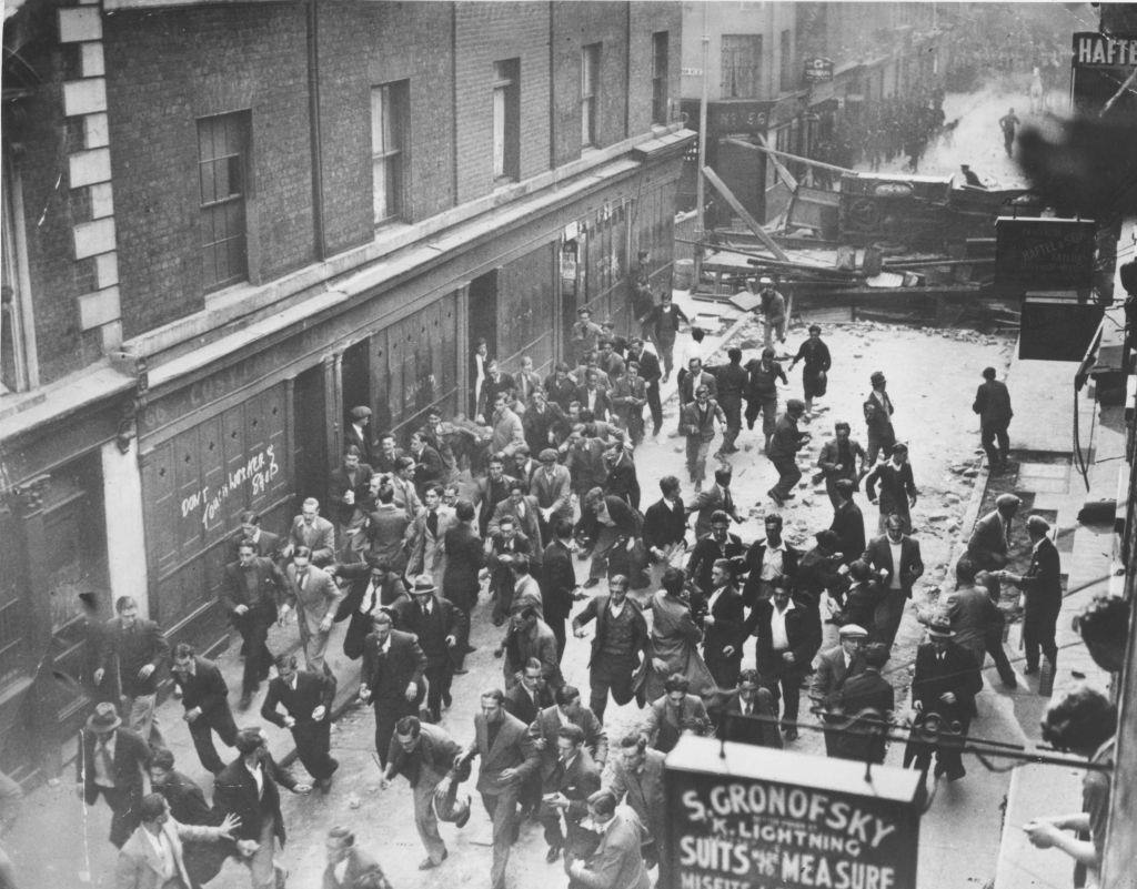 A crowd of demonstrators fleeing as police break down a barricade in Cable Street, Aldgate, east London.