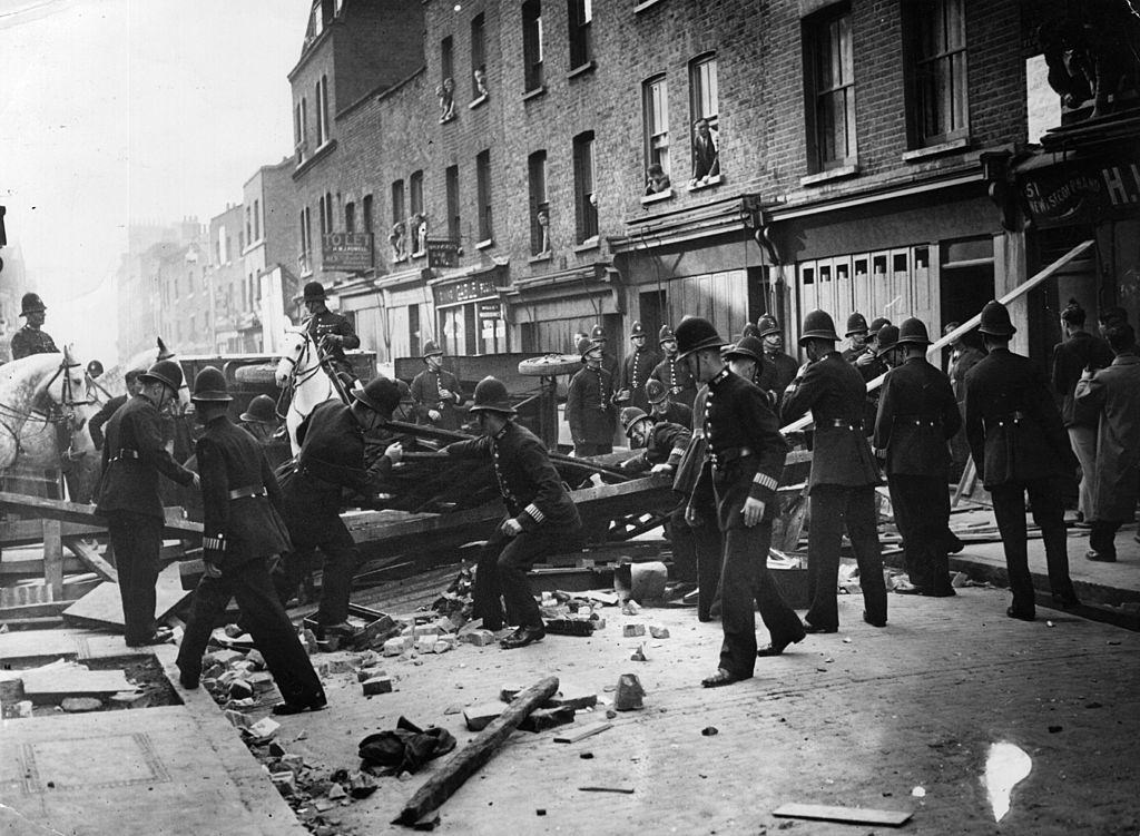 British policemen dismantle a barrier near Mark Lane, London, to make way for a march by supporters of the leader of the British Union of Fascists Oswald Mosley.