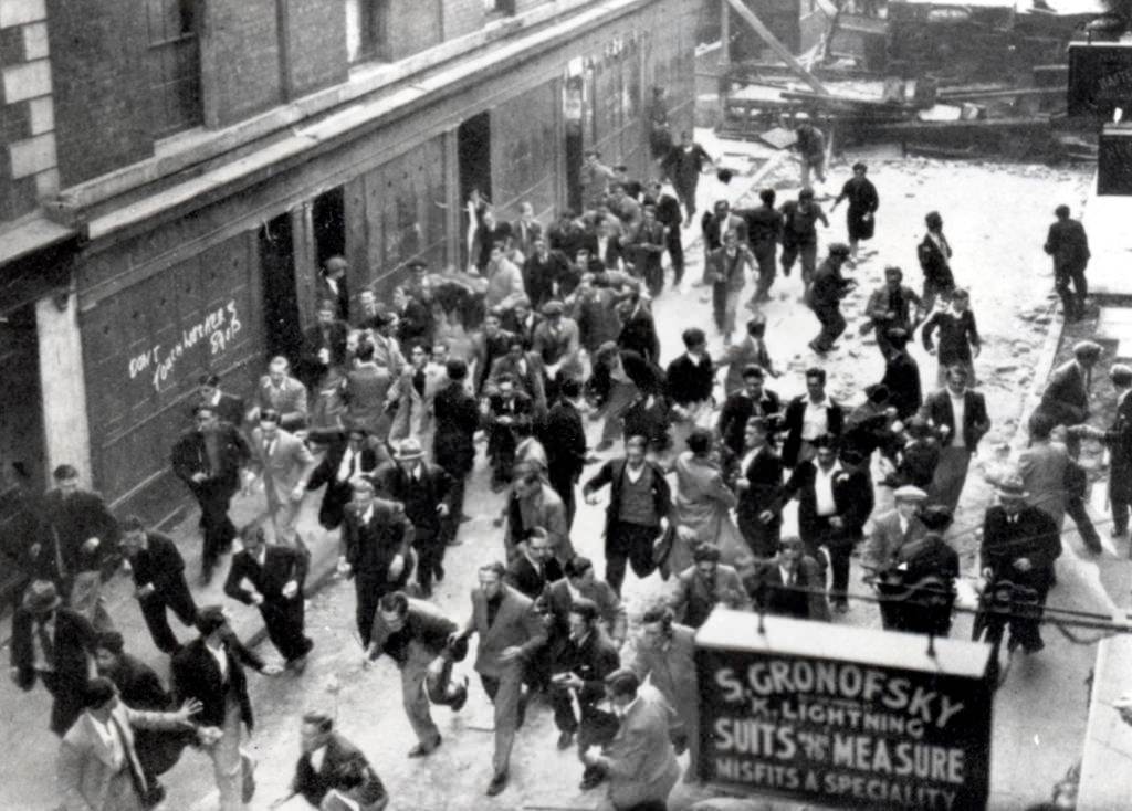 An anti-Fascist crowd, some of them carrying missiles, run from a barricade they have erected near Aldgate.