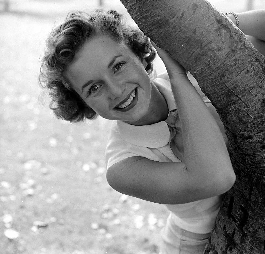 Debbie Reynolds poses behind a tree, 1950.
