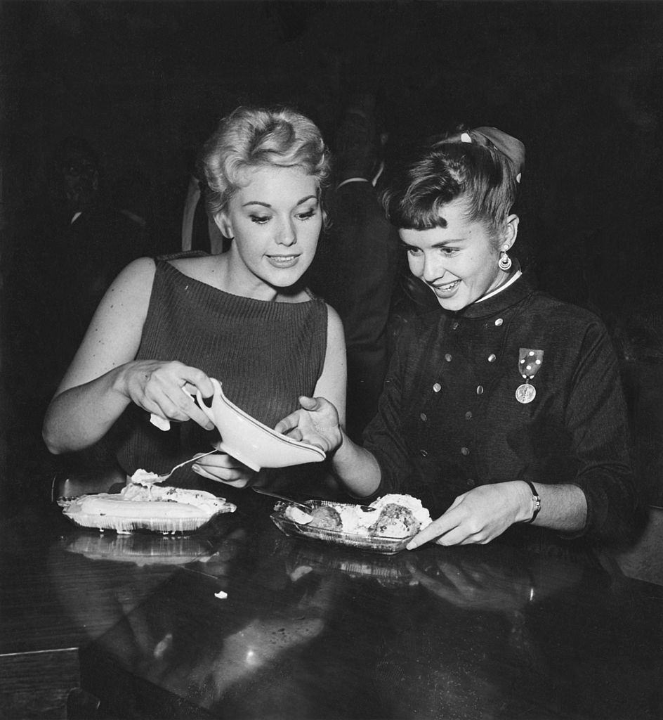 Debbie Reynolds with Kim Novak enjoying ice cream sundaes at a Hollywood party, 1955.