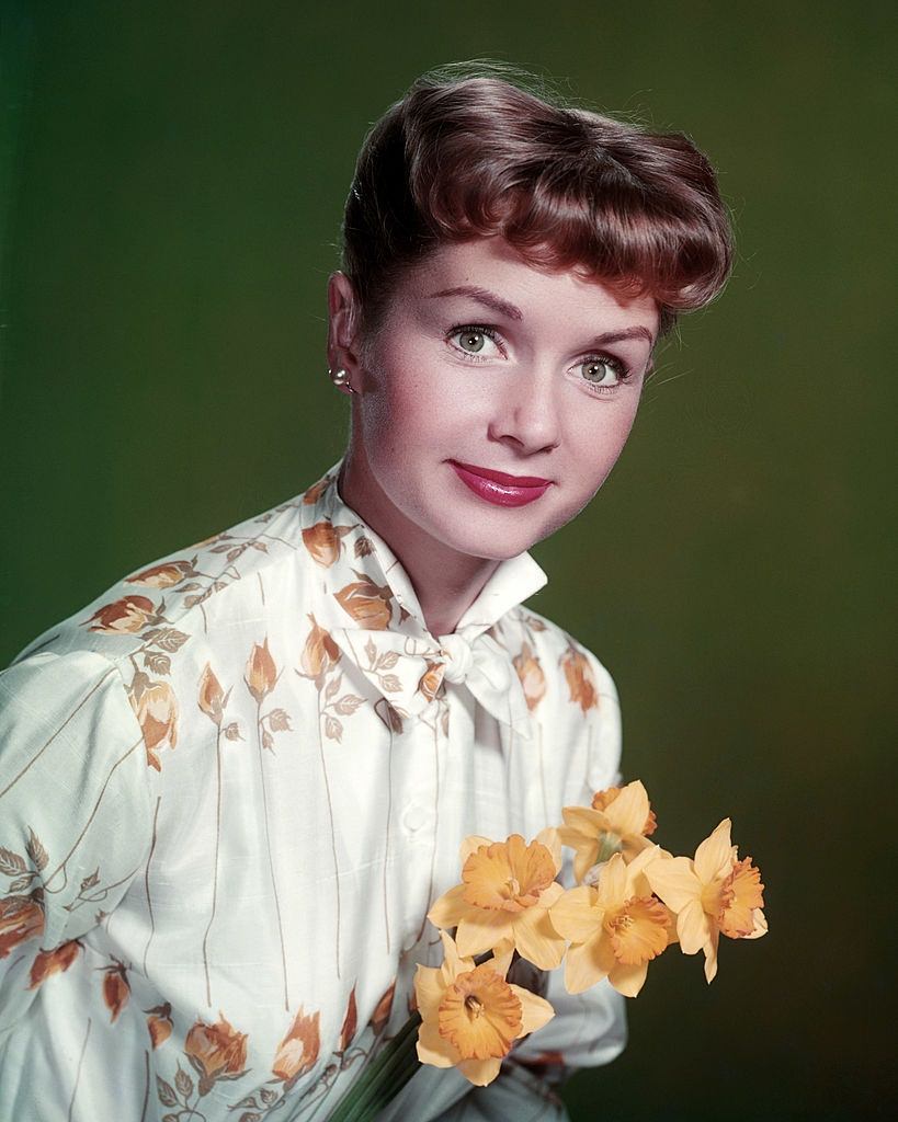 Debbie Reynolds, holding a bunch of daffodils, 1955.