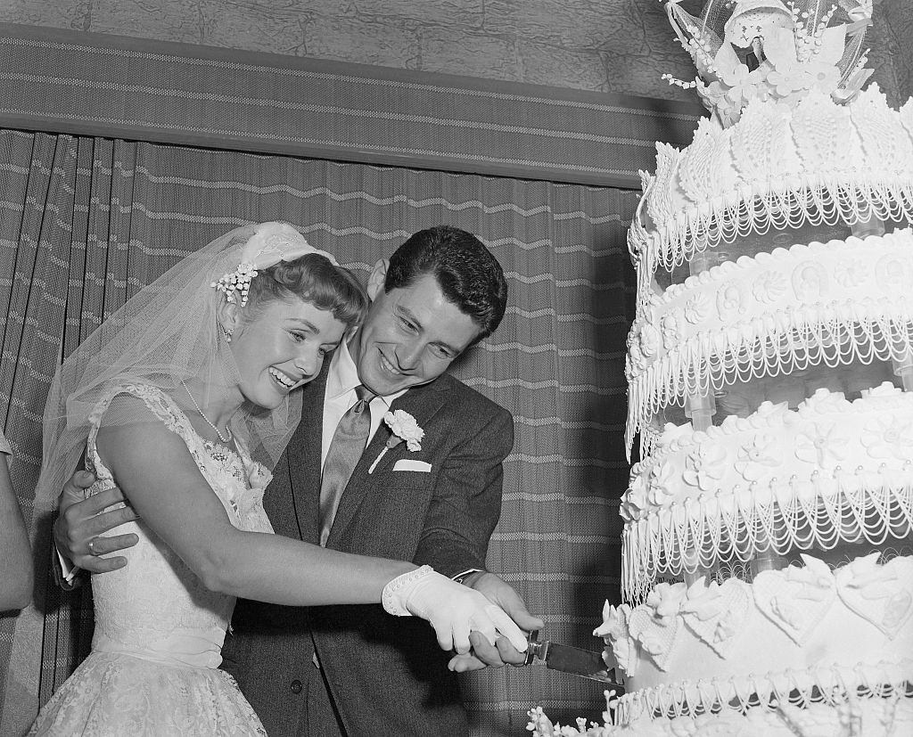 Debbie Reynolds and singer Eddie Fisher cut their towering wedding cake after they were married at Liberty, 1955.