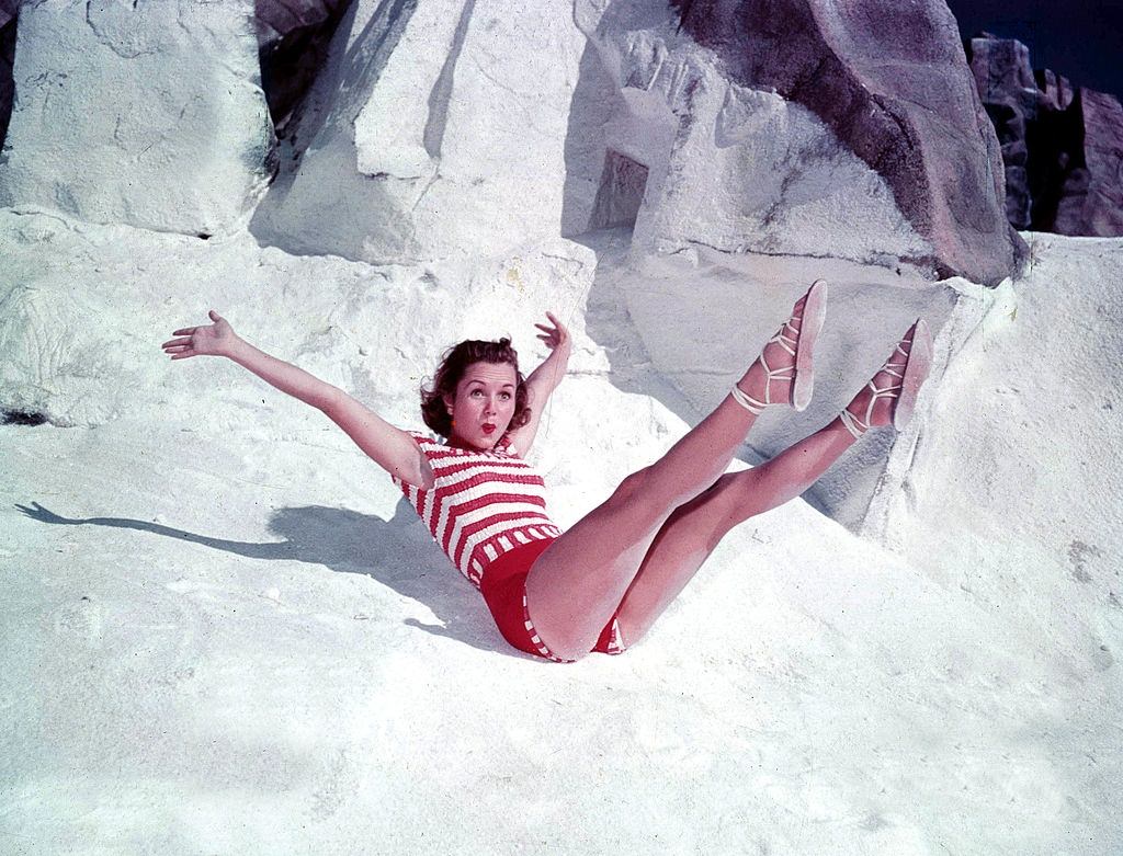 Debbie Reynolds, posing with her legs in the air on some rocks, 1950.
