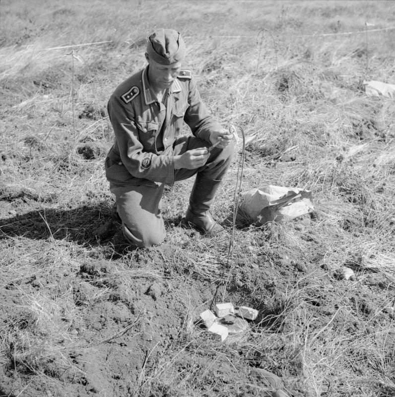 A German prisoner engaged in clearing a minefield near Stavanger fixes a fuse to a Teller mine.