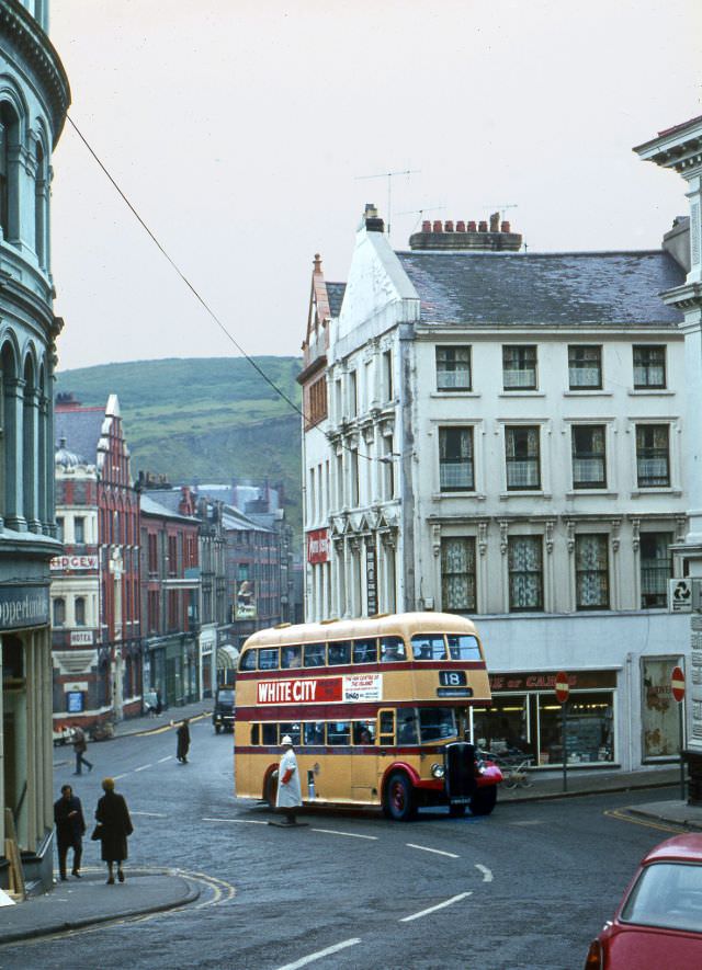 No.71 start to climb Prospect Hill, Douglas past a white-coated & helmeted policeman on a dull morning, 30 June 1971