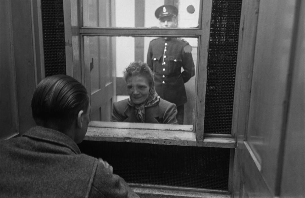 Prison officer Davidson watches as a prisoner talks to a visitor at Strangeways Prison.
