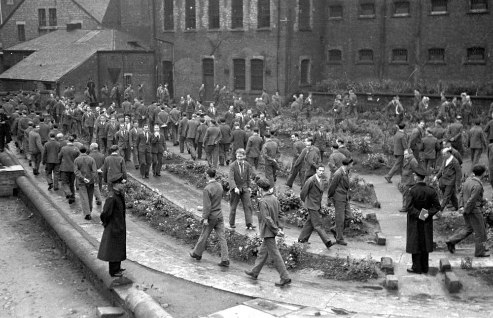 Prison officers watching over prisoners as they take their daily hour of outdoor exercise at Strangeways Prison.